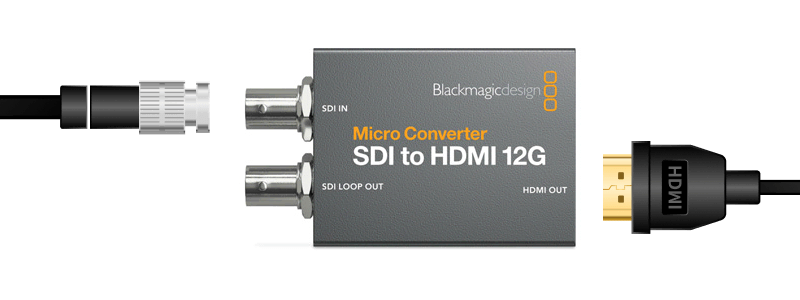 Diagram showing the HDMI-to-SDI conversion chain: laptop with HDMI output connected to a small converter box, long SDI/BNC cable running to a second converter box, then HDMI into the TV